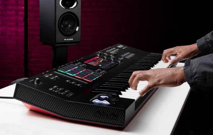 Đàn Akai Professional MPC Key 61 hình đang chụp từ bên trái sang và có 1 cặp bàn tay đang chơi đàn 