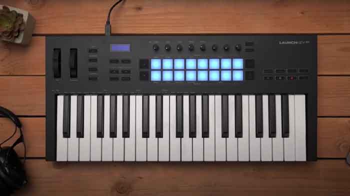 MIDI Controller Novation Launchkey 37 MK3 midi đang được đặt trên bàn và kết hợp với tay nghe 