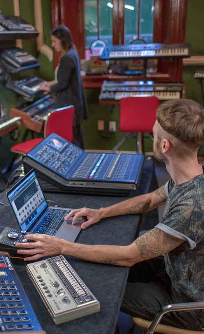 Plug-in cân bằng Arturia EQ Sitral-295 hình đang chụp miêu tả một góc căn phòng có 2 người trong ảnh đang tùy chỉnh thiết bị