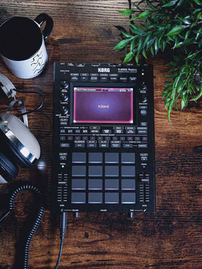 sampler Bộ xử lý âm thanh Korg KAOSS Replay sampletr đang được đặt trên bàn cạnh cốc nước và tay nghe