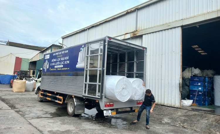 Các cuộn bông lọc bụi G2 bọc nilon gọn gàng đang được bốc xếp lên thùng xe tải tại kho Quế Võ