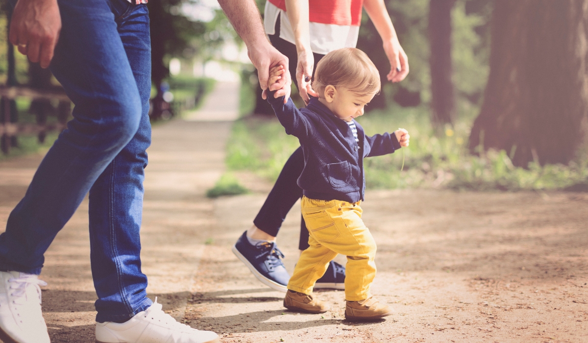 Bé mới biết đi được cha mẹ nắm tay tập đi ngoài trời, giai đoạn vàng để phát triển dáng đi chuẩn và phòng tránh tật bàn chân.