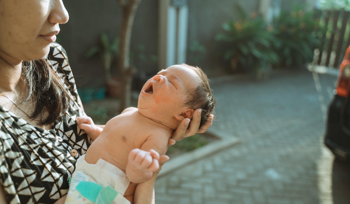 Mẹ cho em bé tắm nắng dưới ánh sáng mặt trời, thể hiện sự chăm sóc và tầm quan trọng của việc bổ sung vitamin D cho trẻ