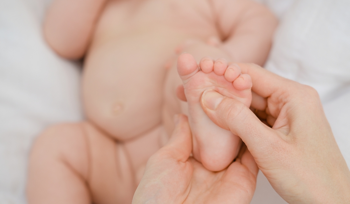 Hình ảnh một người mẹ đang mát xa chân cho trẻ em, thể hiện sự chăm sóc và yêu thương. Bàn tay của mẹ nhẹ nhàng xoa bóp bàn chân của bé, giúp thư giãn cơ bắp và cải thiện lưu thông máu