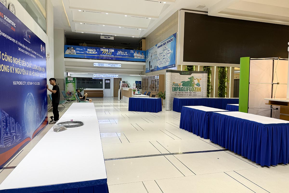 Bàn IBM phủ khăn trắng và váy xanh dọc hành lang khu hội thảo y tế