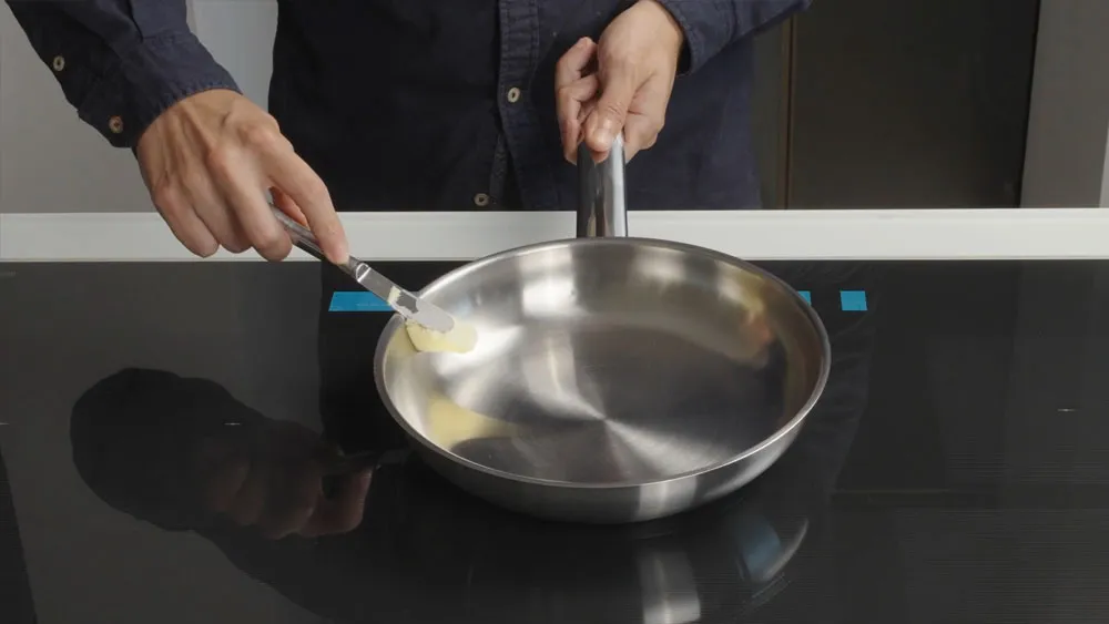 Thêm bơ vào chảo inox để chuẩn bị nấu ăn