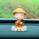 Tượng chú tiểu gật đầu đội nón áo cam cưỡi mây