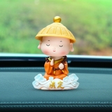 Tượng chú tiểu gật đầu đội nón áo cam cưỡi mây