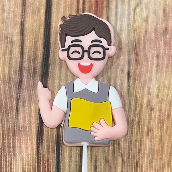 Tượng nhựa dẻo- chàng trai (thầy giáo) áo ghi cầm sách màu vàng.
