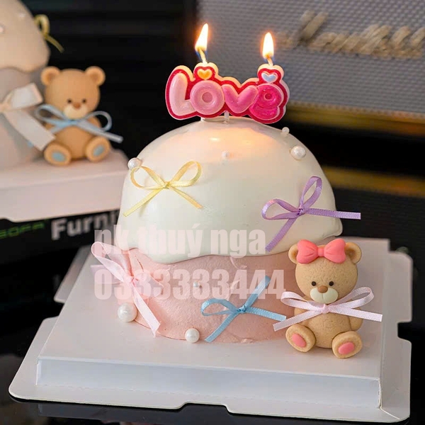 Tượng nhựa -gấu màu vàng nâu cài nơ hồng (bàn chân hồng).