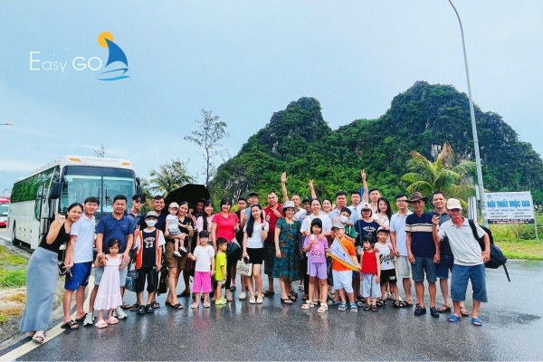 Đoàn du chụp ảnh kỷ niệm trước núi xanh trong chuyến đi vui vẻ.