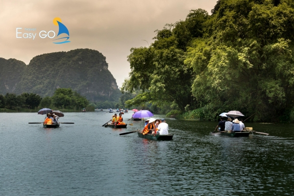Những chiếc thuyền nhỏ chở du khách lướt nhẹ trên dòng sông giữa núi non xanh biếc.