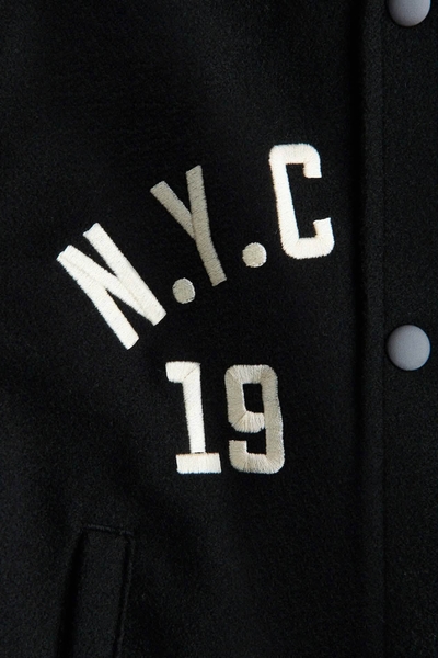 Áo khoác bomber N.Y.C CLUB 1973 H&M màu đen phối tay da trắng