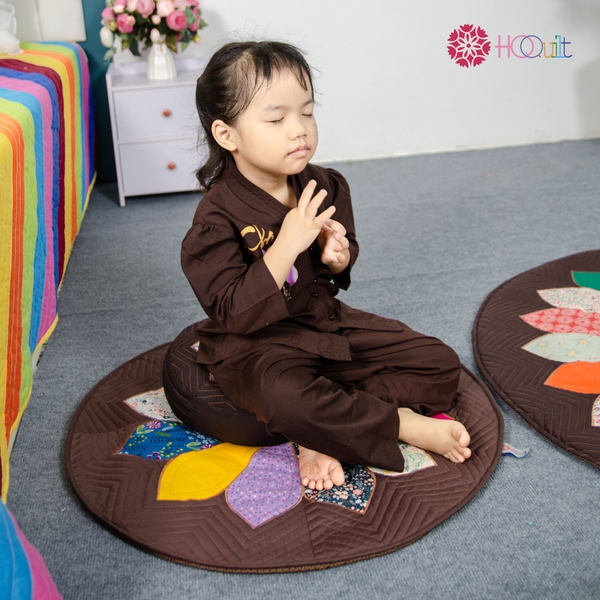 A child meditating on the 70 cm Daisy Rug 