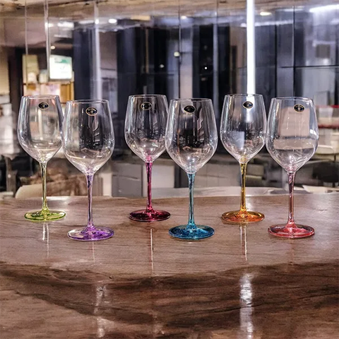 So sánh hai ly whisky trên quầy bar gỗ sồi. Ly pha lê Châu Âu bên trái trong suốt, lấp lánh với rượu màu đậm. Ly thủy tinh bên phải mờ đục, nhiều bọt khí nhỏ, thành ly dày hơn.