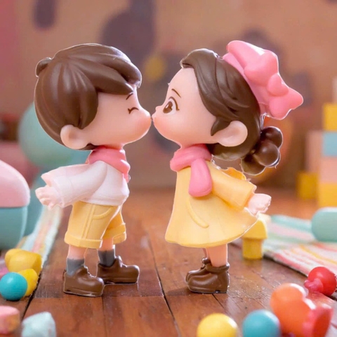 Đôi em bé nhựa đặc - váy vàng, quần vàng, nơ hồng, giày đen.