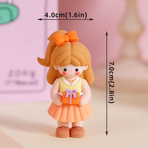 Tượng nhựa đẹp - em bé gái váy màu vàng cam, cài nơ màu cam,tay cầm hộp quà Q9051.
