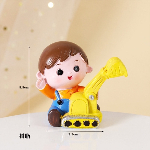 Tượng sứ bé trai máy xúc (áo cam, quần xanh).
