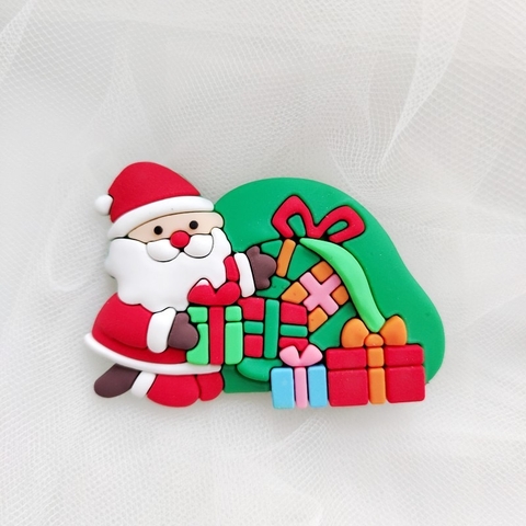 Tượng nhựa dẻo-Ông già noel cầm hộp quà và ôm túi quà màu xanh.