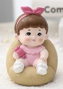 Tượng em bé gái cài nơ hồng ngồi ghế (sứ).