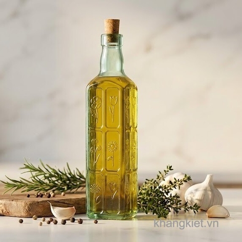 Chai thủy tinh vuông nút bần C.H Fiori 500ml đựng dầu oliu đặt trên bàn bếp cùng thảo mộc và tỏi