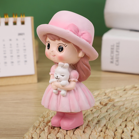 Bé gái đứng MŨ HỒNG ôm thỏ SỨ