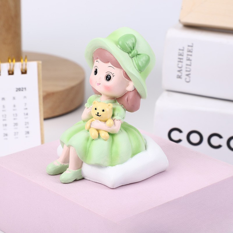 Bé gái ngồi MŨ XANH ôm GẤU SỨ