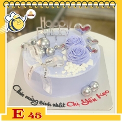 Bánh kem E45 nền màu tím nhạt với 2 đóa hoa màu tím nở rộ cùng phụ kiện tinh tế