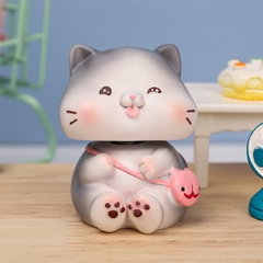 Trang trí sứ con mèo xám ngồi cười đeo túi hồng (cổ lò xo)