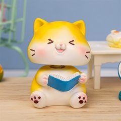 Trang trí sứ con mèo vàng ngồi cười đọc sách (cổ lò xo)