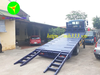 Sàn chở máy Thaco Ollin 700C nghiêng với hai cầu dẫn gập đã hạ xuống mặt sân