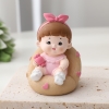 Tượng em bé gái cài nơ hồng ngồi ghế (sứ).