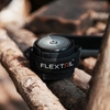 Loa mini Flextail Tiny Speaker màu đen đặt trên khúc gỗ, cận cảnh logo Flextail