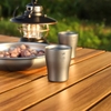 Ly Uống Rượu Keith Titanium Wine Cup 10ml trên bàn gỗ cạnh đĩa hạt và đèn lồng cắm trại